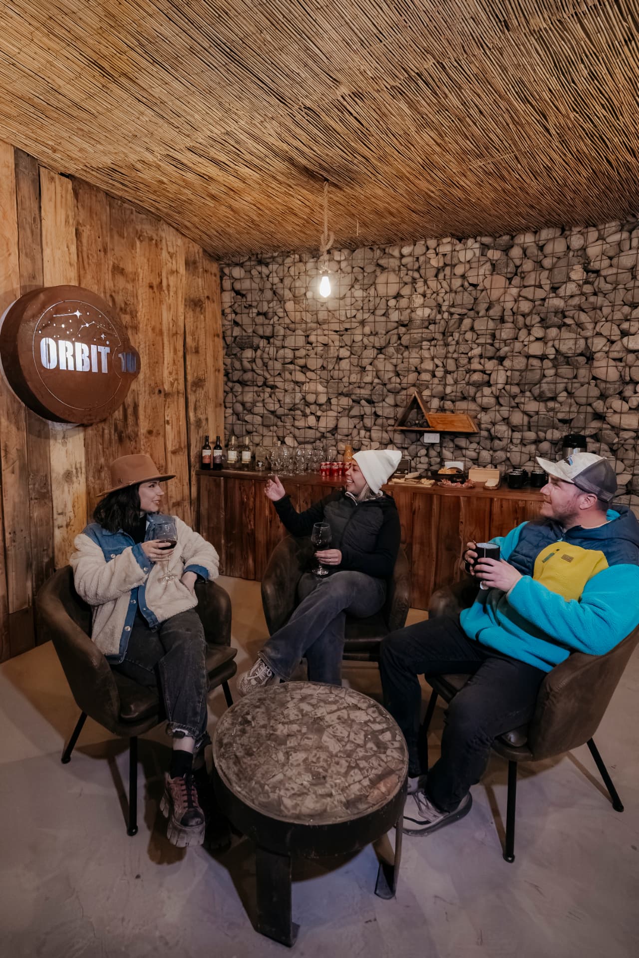 Viajantes conversando com taças de vinho no lounge aquecido do Tour Astronômico - Orbit 10