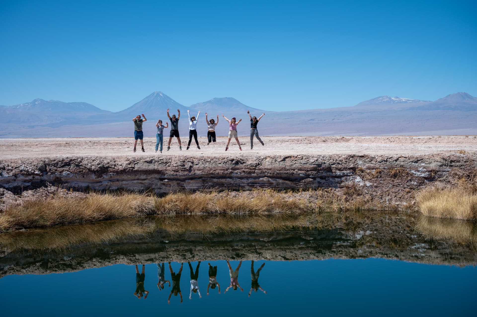 Equipe celebrando com salto em frente aos vulcões do Atacama