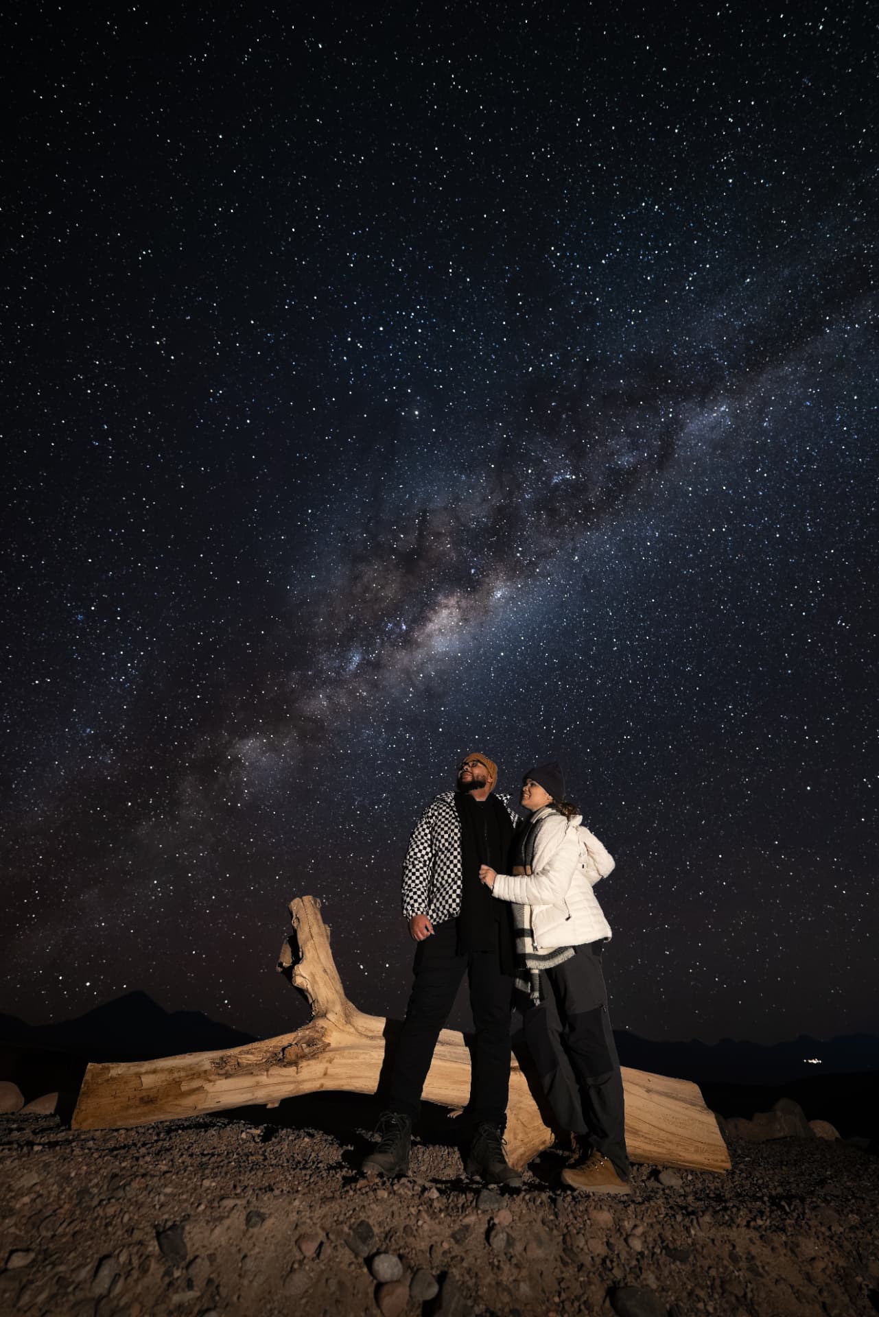 Casal sob a Via Láctea em noite estrelada no Deserto do Atacama