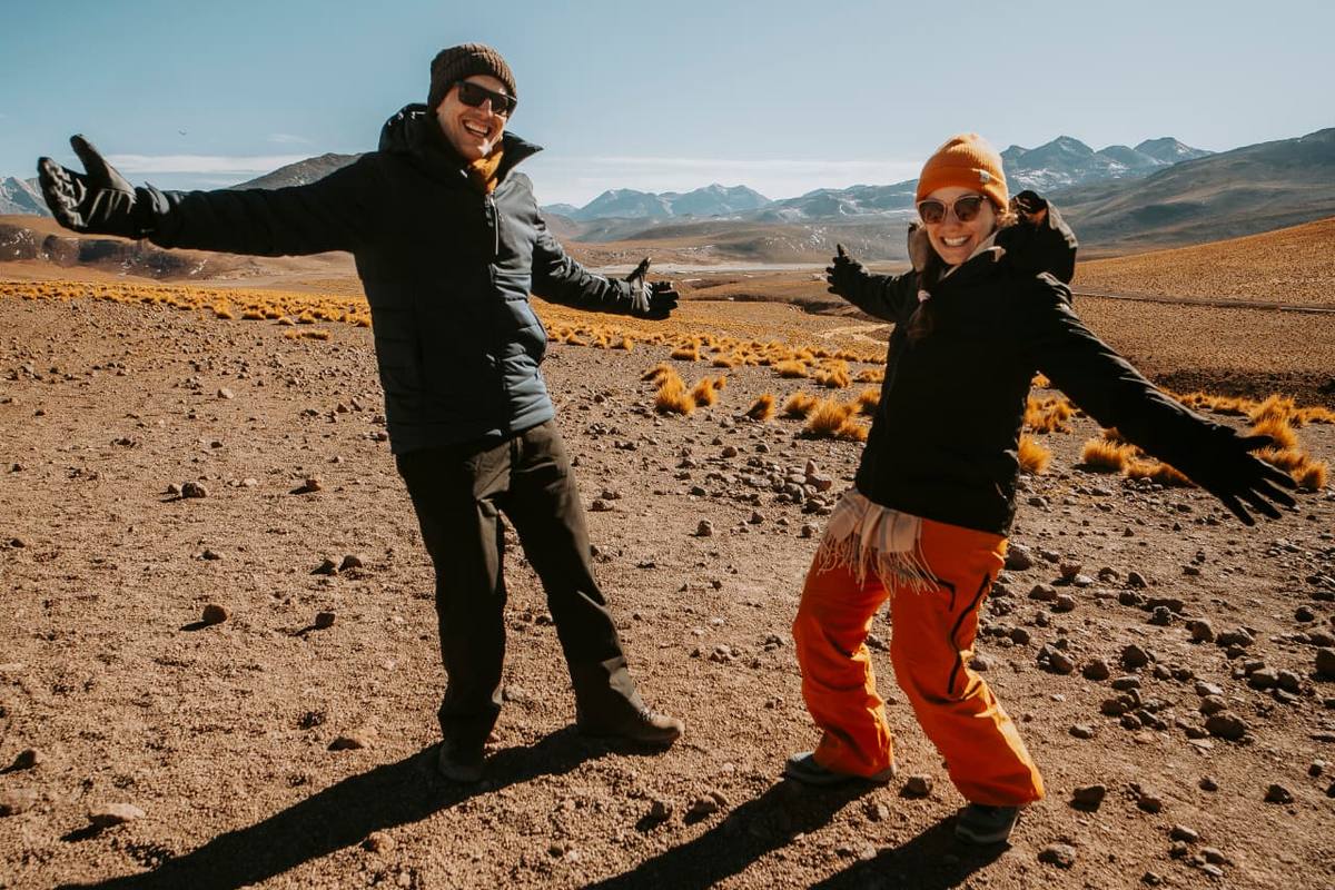 Casal celebrando a alegria de viver o Deserto do Atacama com os braços abertos