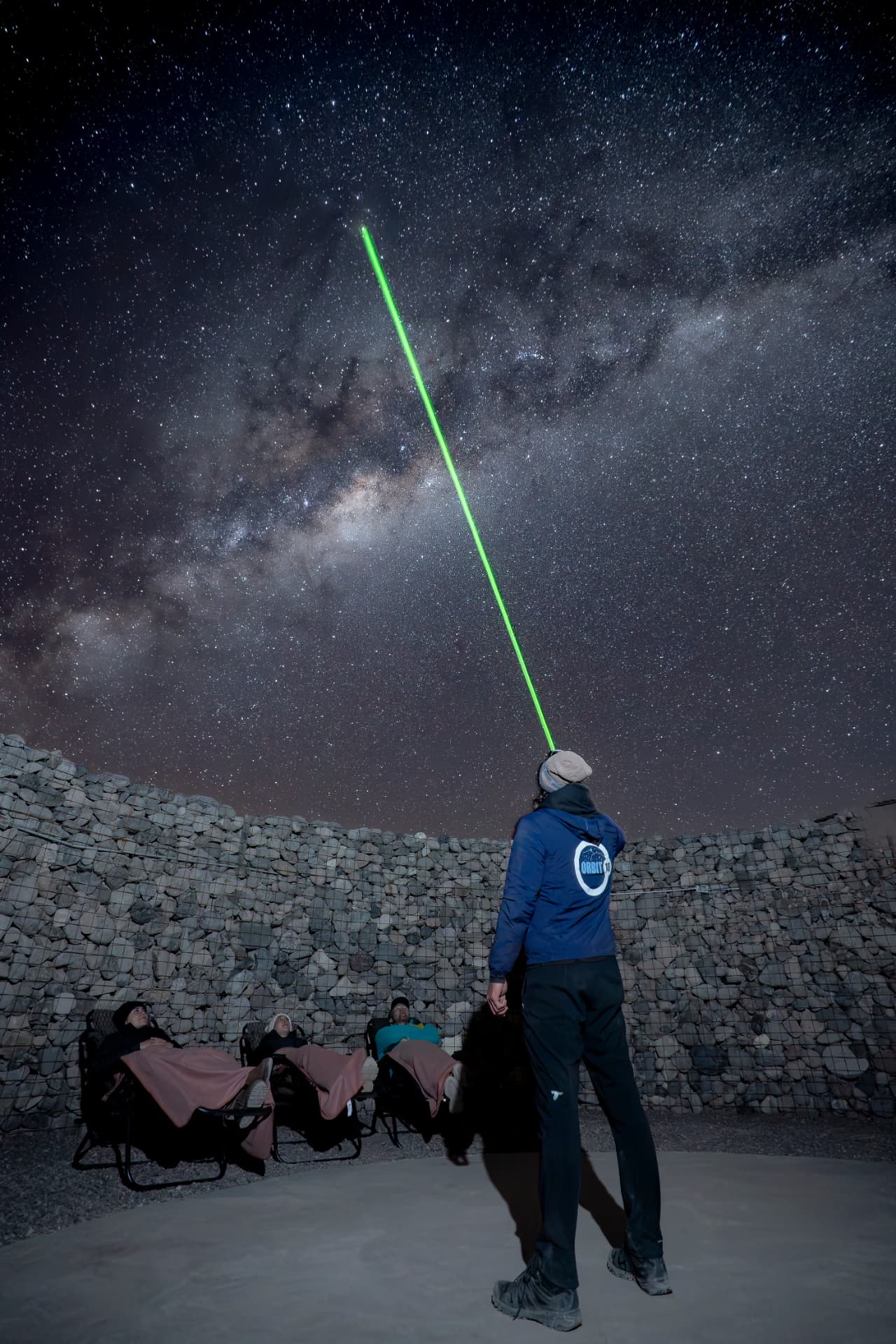 Guia apontando laser verde para o céu estrelado durante a observação astronômica