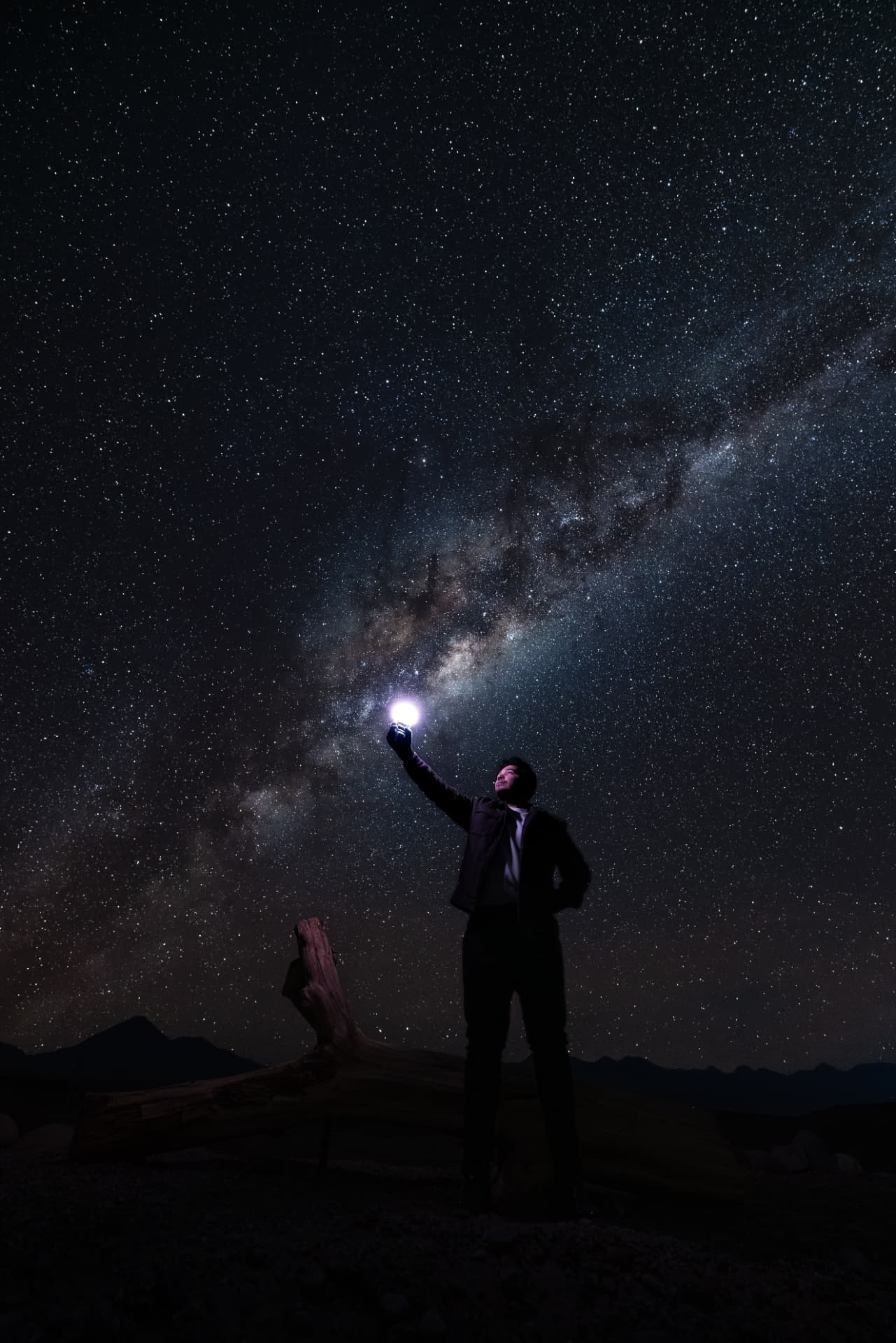 Visitante iluminando o céu noturno do deserto com uma lanterna